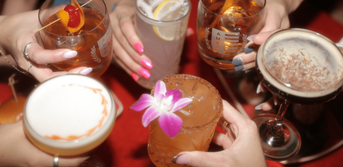 Six hands holding cocktails.