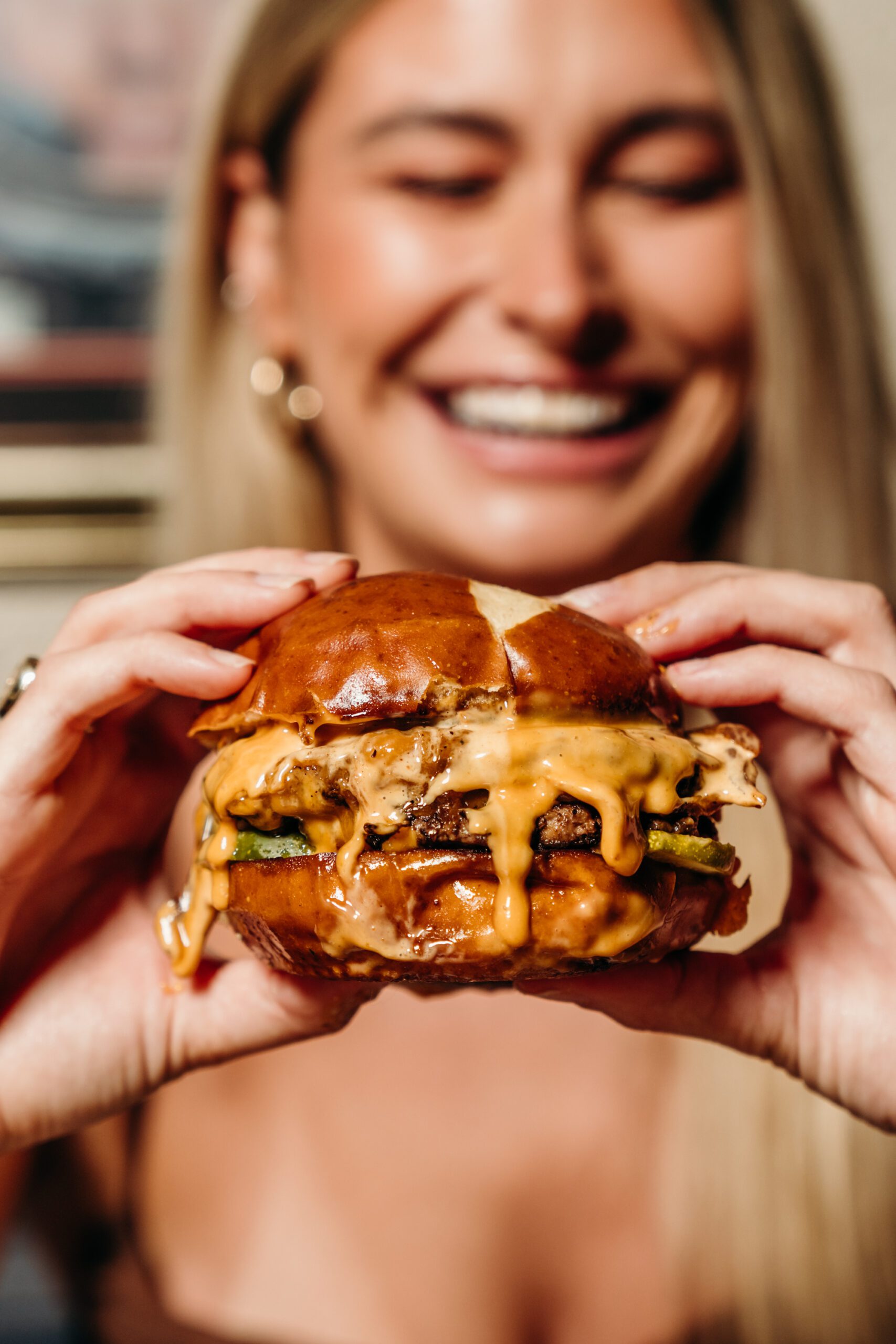 Smiling woman is holding a burger.