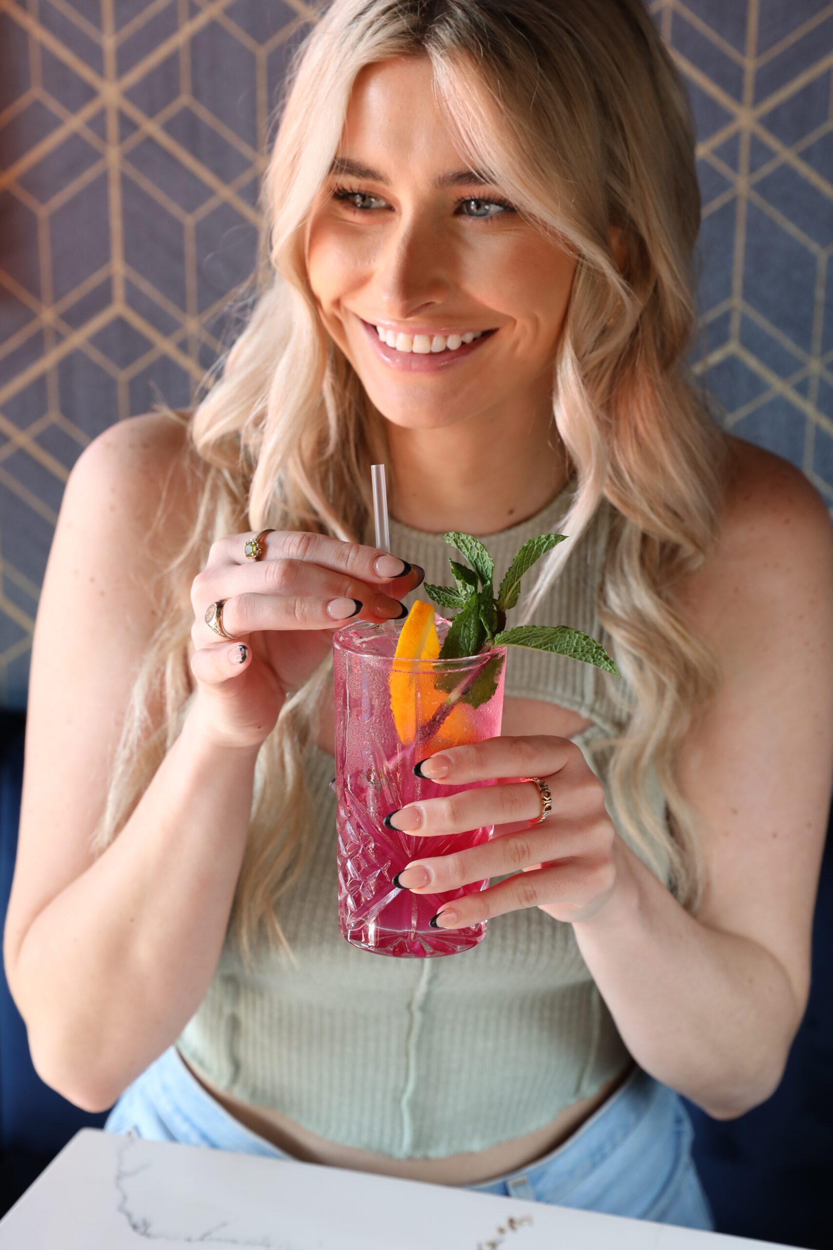 Happy blonde woman is drinking cocktail.