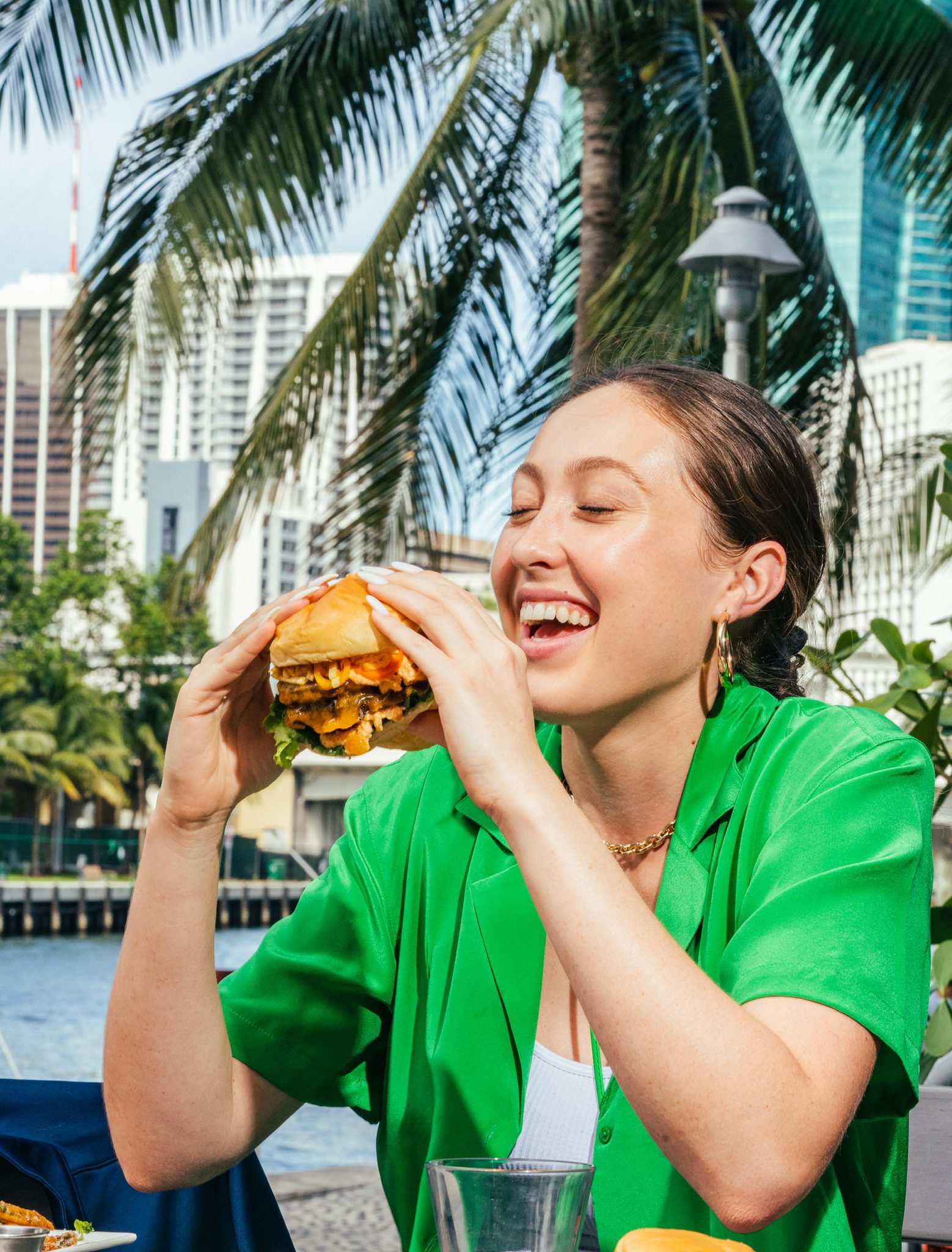 A brown haired woman is ready to bite into a delicious burger.