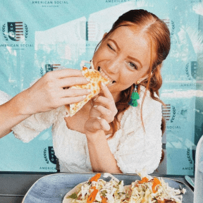 A girl is eating a taco.