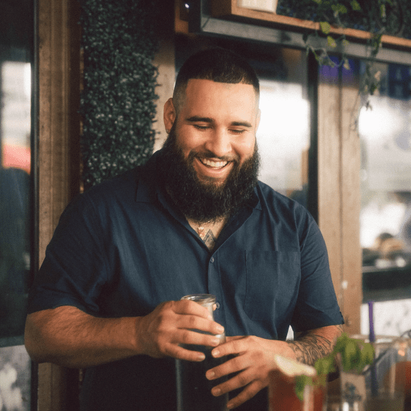 A smiling man is making cocktail.