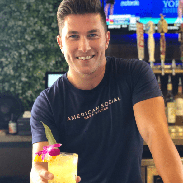Bartender at American Social holding a cocktail.