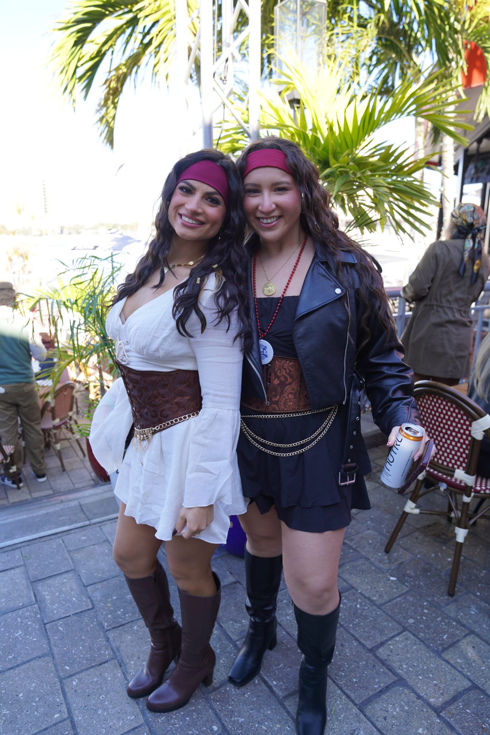 Two women wearing clothing pose for the camera, enjoying festive food and beverage.